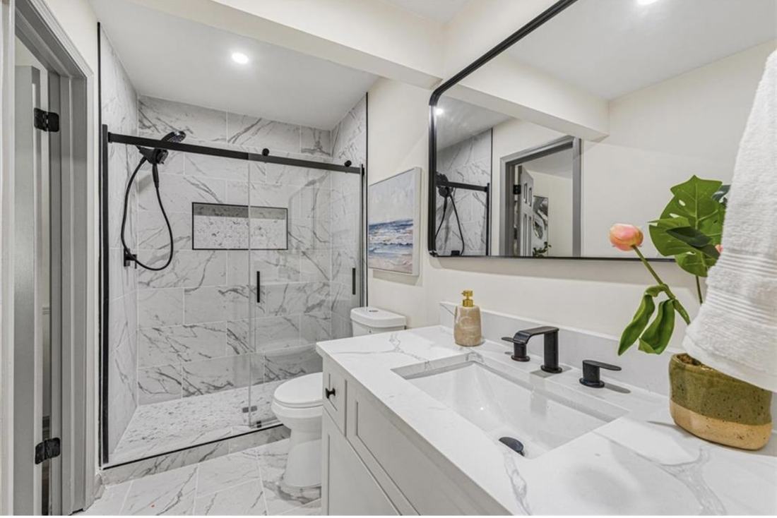 Remodeled bathroom with marble tile shower and quartz vanity