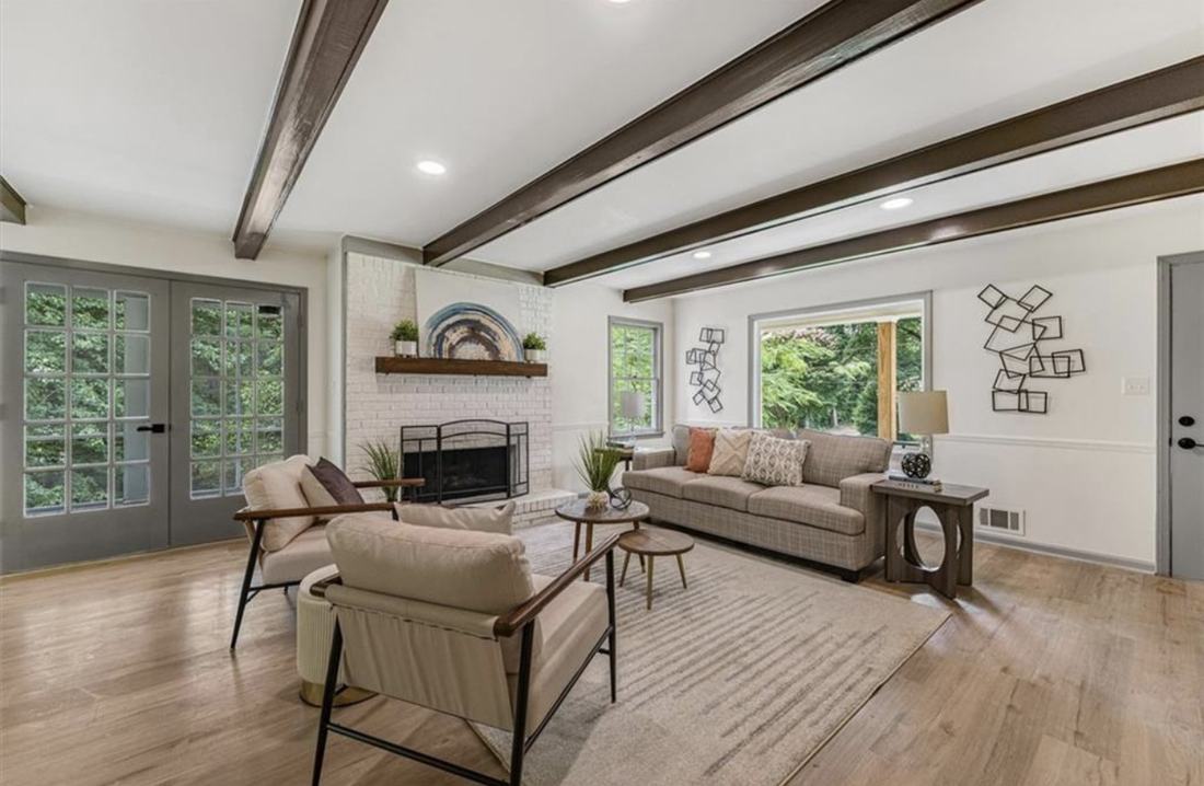 Renovated living room with exposed beams, painted brick fireplace and new flooring